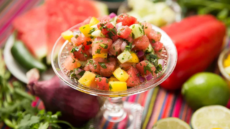 Refreshing Watermelon Salsa in small glass dish surrounded by produce