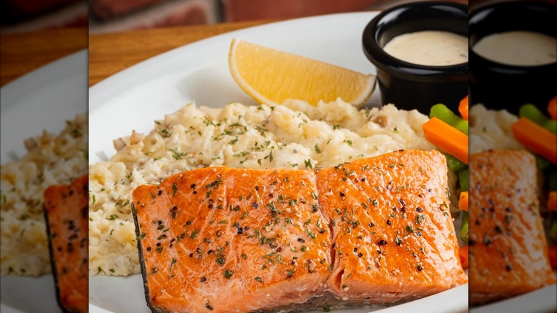 Texas Roadhouse's grilled salmon on plate with lemon, dipping sauce, veg, and mashed potatoes