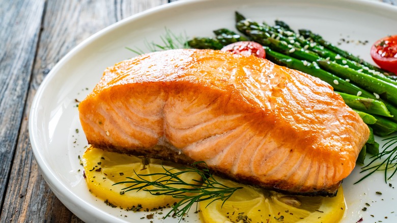 Grilled salmon on plate with lemon slices and asparagus