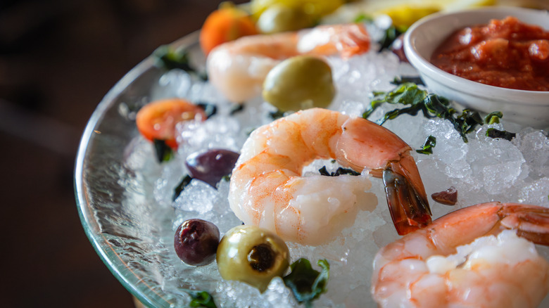 Shrimp cocktail on ice with olives and cocktail sauce