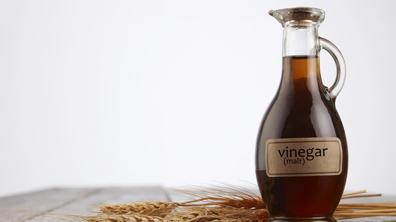 Bottle of unbranded malt vinegar on wooden table