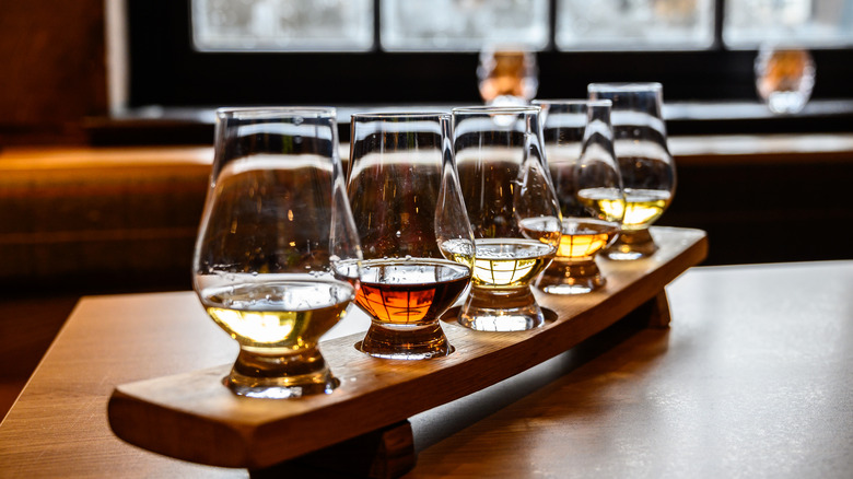 A row of five whiskey glasses set up on a board, ready to be tasted