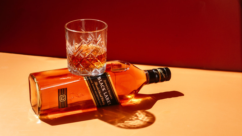 A bottle of whiskey perched on top of a bottle of Johnnie Walker Black Label
