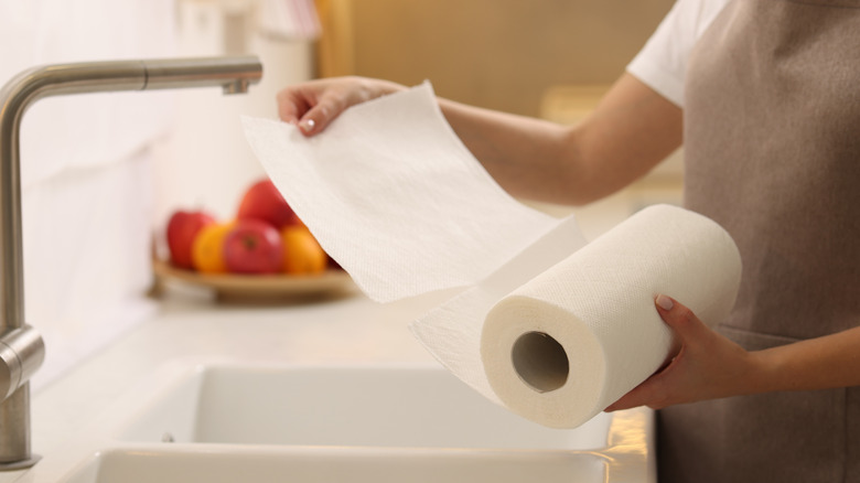 Person in apron tearing off sheet of paper towel
