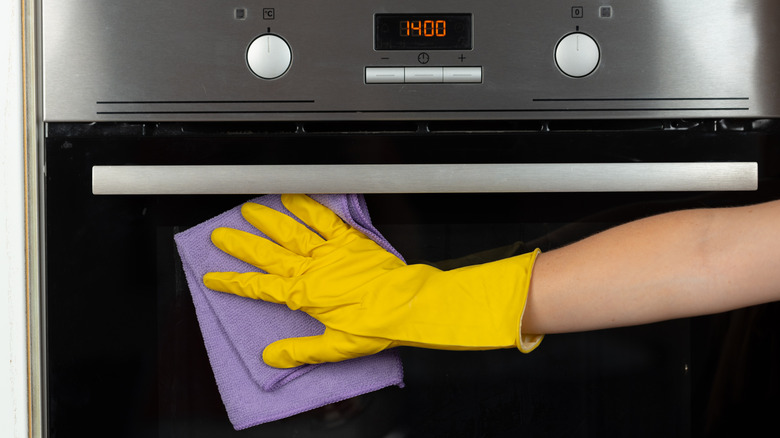 Woman's hand using microfiber cloth to clean oven door
