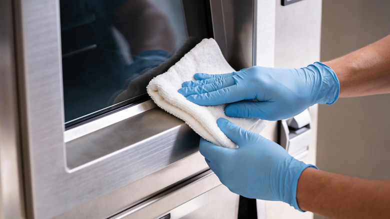 Wiping the surface of a stainless steel appliance with a white cloth