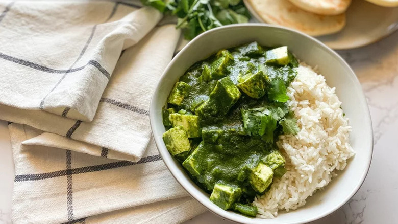 bowl of palak paneer with rice next to table cloth
