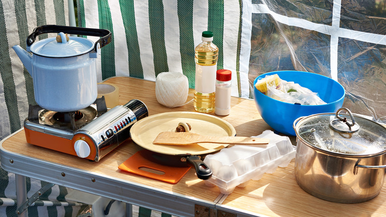 Portable stove with a kettle and crockery placed on wooden table