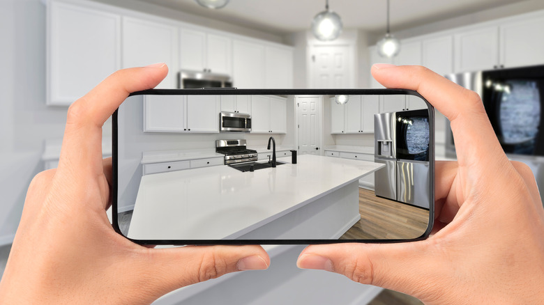 Person using a cell phone to take a photo of an empty kitchen
