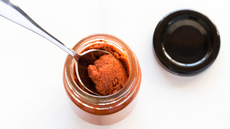 Jar of red curry paste, with a spoon removing some from the jar