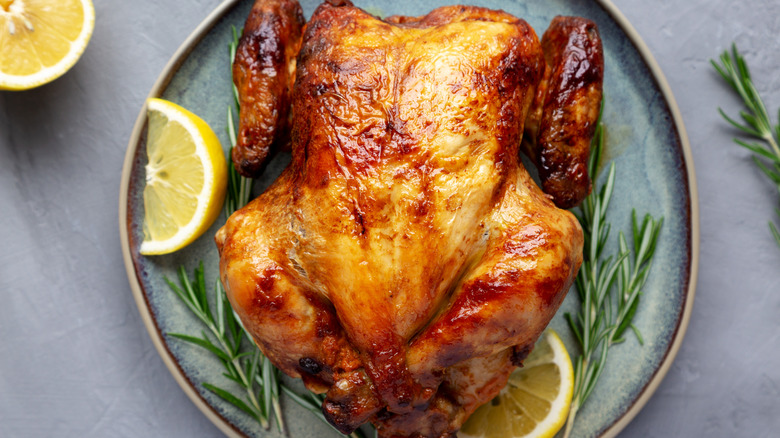 Roasted chicken served with lemon slices and fresh rosemary
