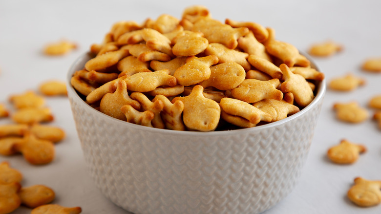White bowl filled with goldfish crackers, with some spilling outside the bowl