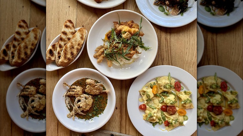 Assortment of dishes including ravioli  and breads on wooden table