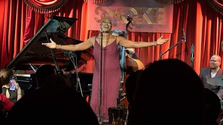 Group of musicians performing on-stage in front of red curtain