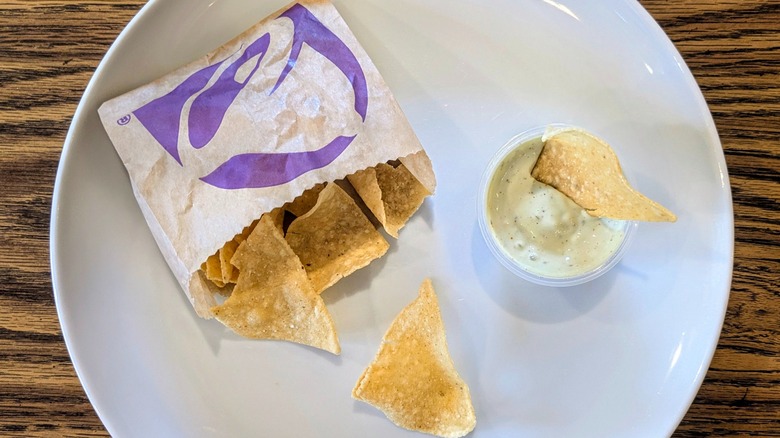 A cup of ranch and a bag of Taco Bell chips on a white plate