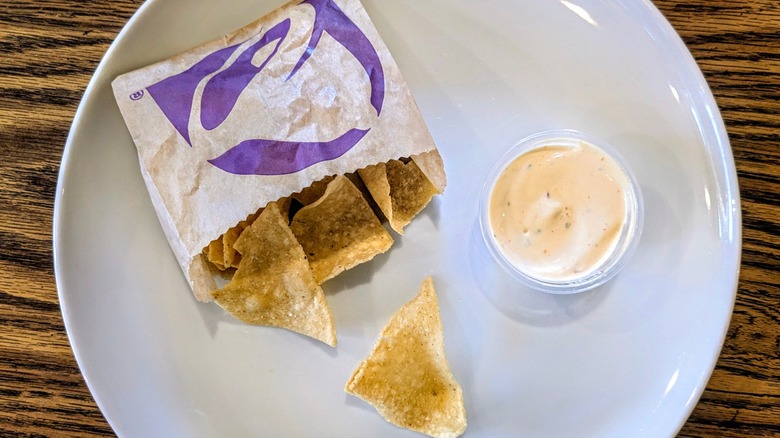 A cup of ranch and a bag of Taco Bell chips on a white plate