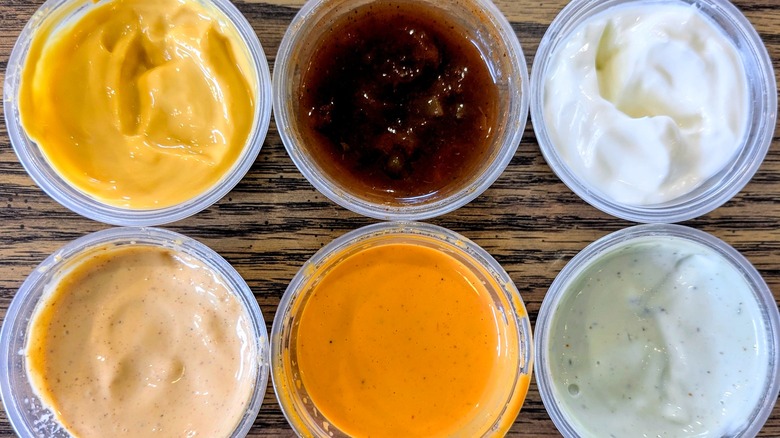 A close up of six different colorful sauces in plastic cups