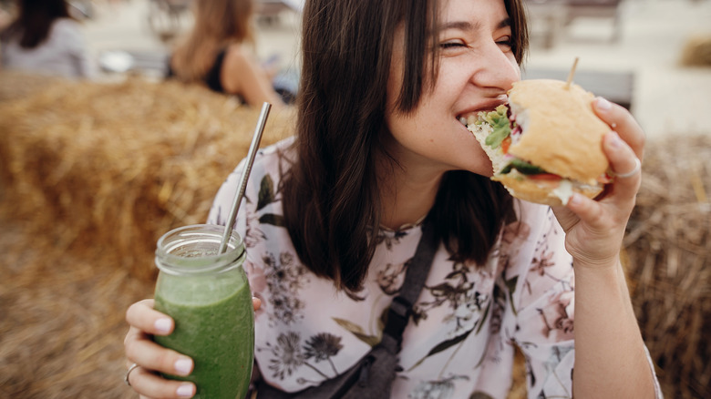 Happy girl eating a veggie burger and smoothie
