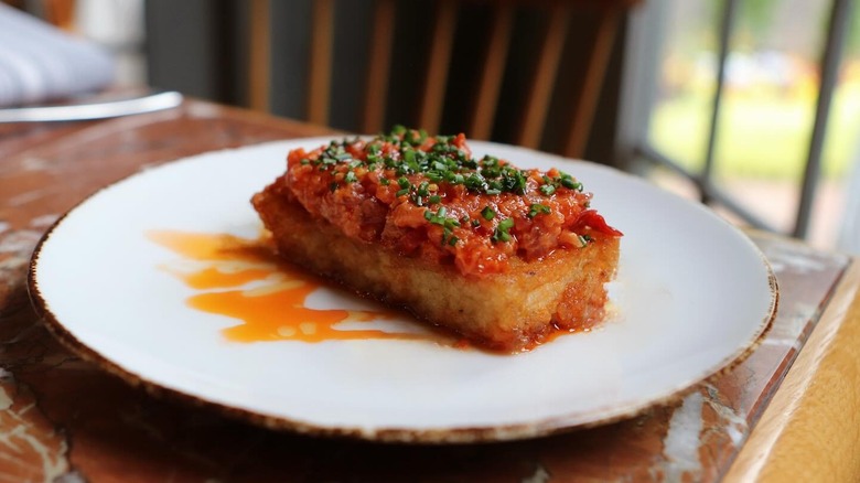 white plate with seared fish topped with chopped tomatoes