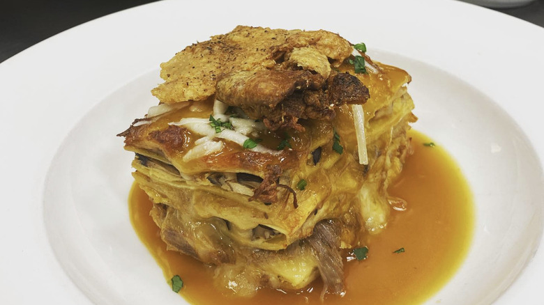 white dish with stacked tortillas in broth