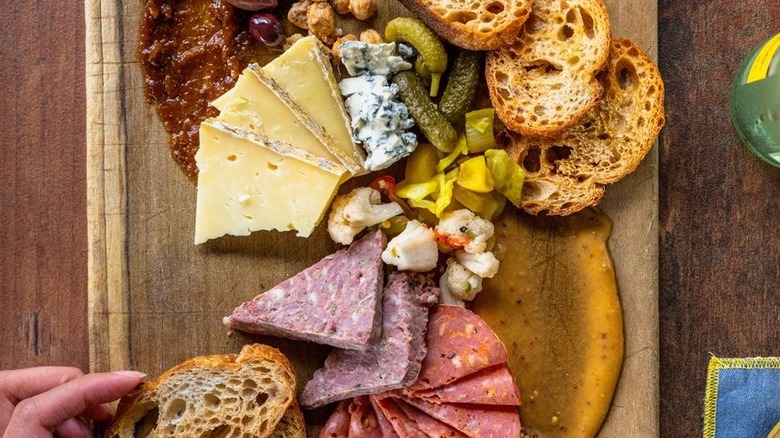 Charcuterie board with hand holding bread