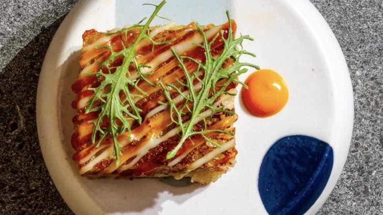 white plate with smokey Spicebush Sausage Sandwich and egg yolk