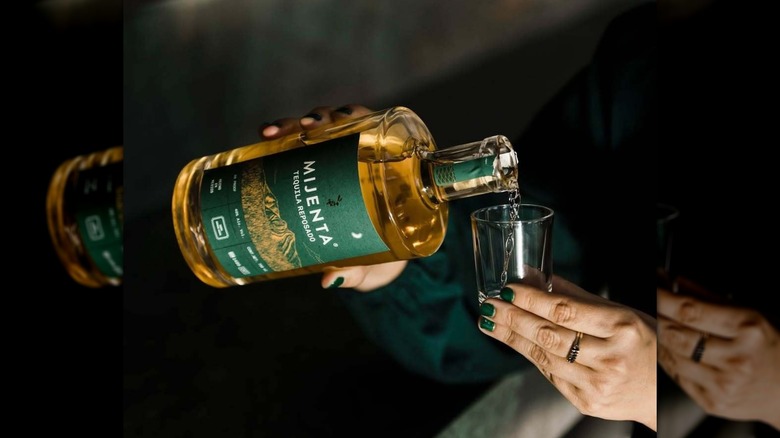 Hand pouring a bottle of Mijenta Reposado