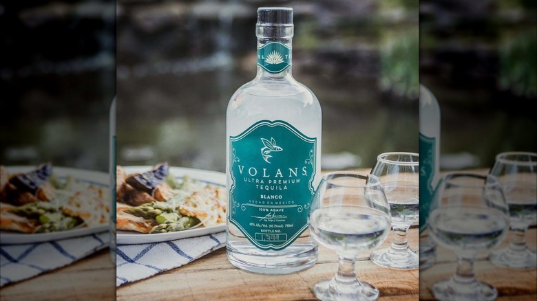 Bottle of Volans Tequila on a table with food