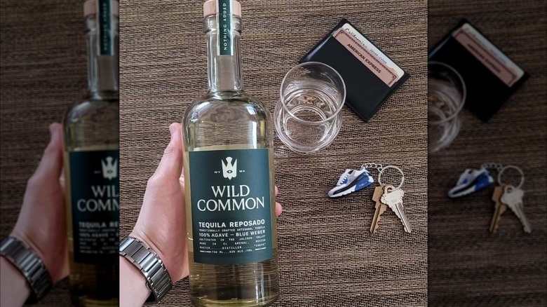 Bottle of Wild Common Reposado with keys and a wallet