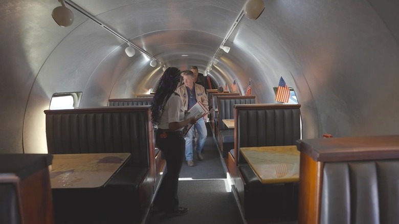 A server shows guests to a table inside The Airplane Restaurant