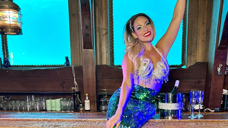 A mermaid performer sitting on the bar at The Wreck Bar