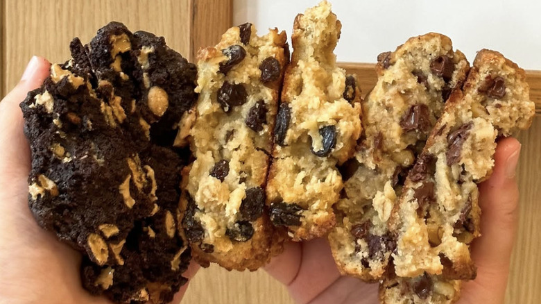 two hands holding a series of split open cookies in various flavors