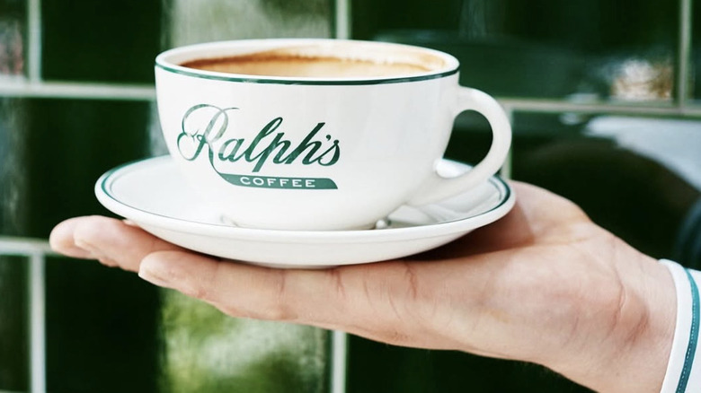 a hand with a cup of Ralph's Coffee resting on it