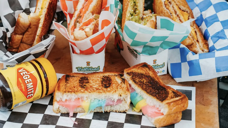 a rainbow grilled cheese alongside other sandwiches and a jar of vegemite
