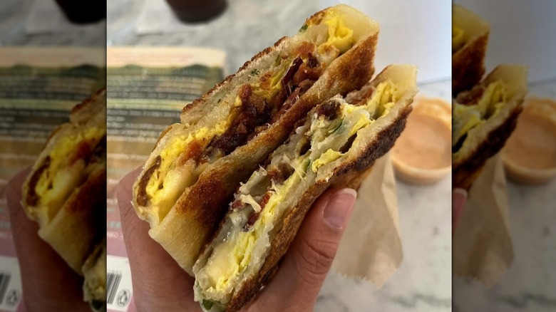 a scallion bacon, egg, and cheese on a silver tray with a side of sauce