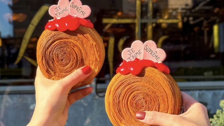 two hands holding out round croissant pastries