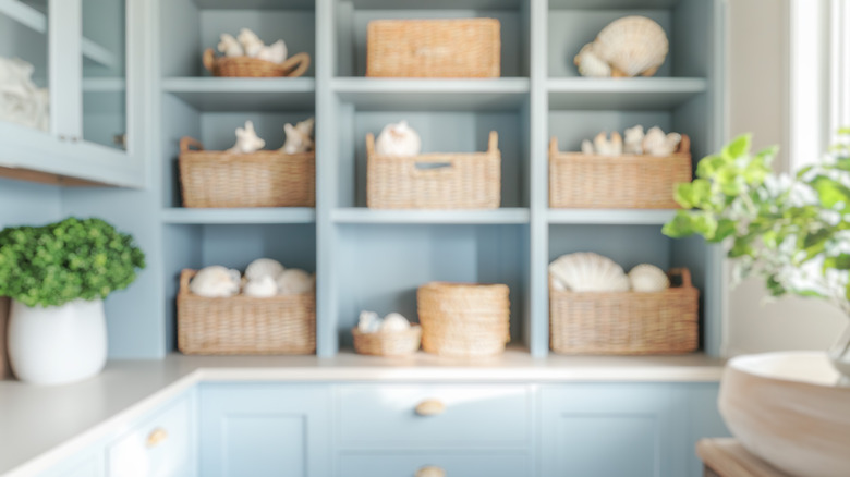 Blurred background of a coastal pantry with blue shelves and wicker baskets