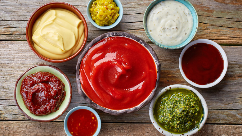 Various dips and sauces in small bowls on a wood background
