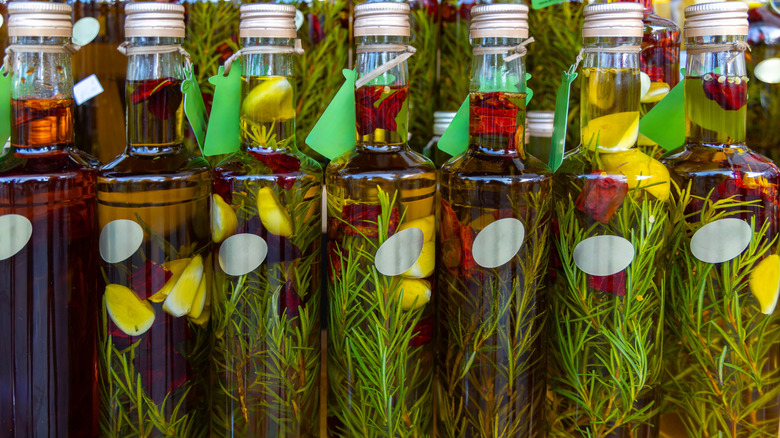 A close up of bottles of olive oil infused with rosemary, lemon, and peppers