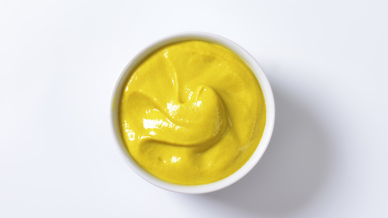 Dijon mustard in a white bowl isolated on a white background