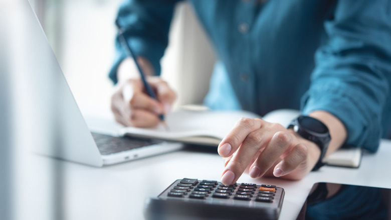 Close-up of a hand using a calculator to decide the budget