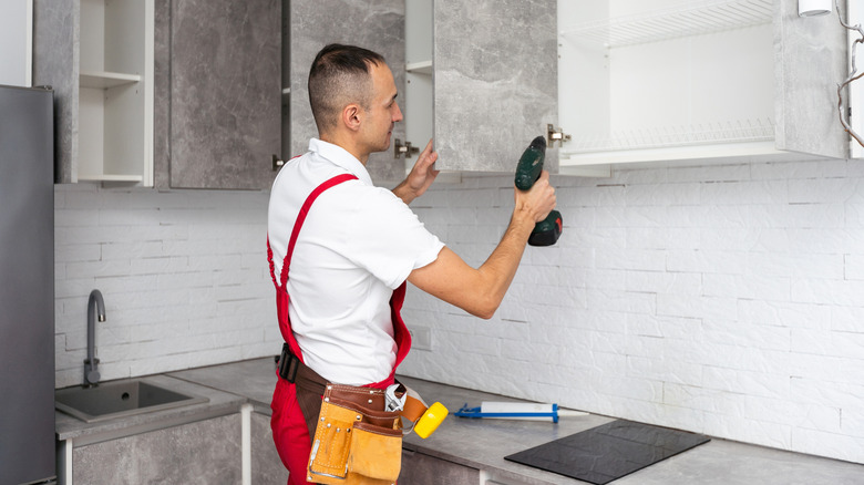 Worker installing new cabinets in a bright kitchen