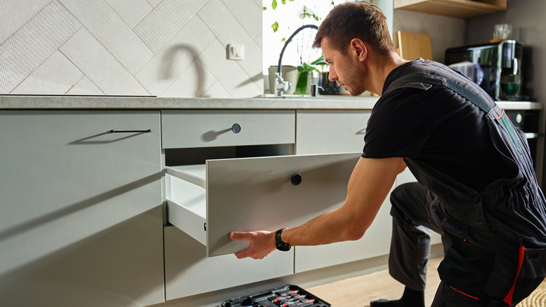 Man fitting a kitchen drawer into the cabinet