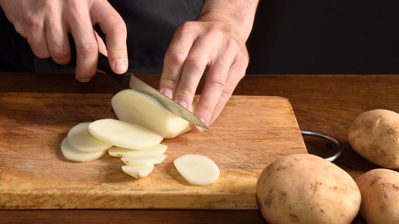 A person slicing potatoes