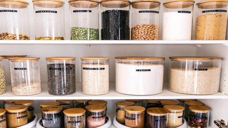 Organized kitchen cabinet with labeled jars in transparent containers
