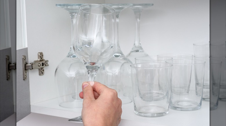 Person grabbing wine glass from cabinet