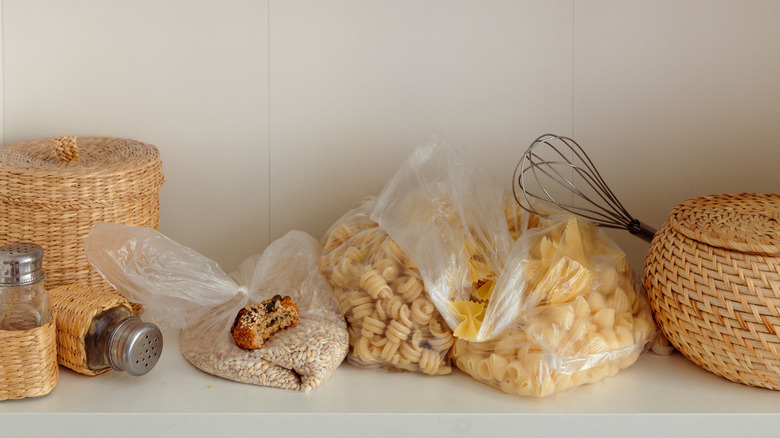 open kitchen cabinet with cluttered food packets on shelves