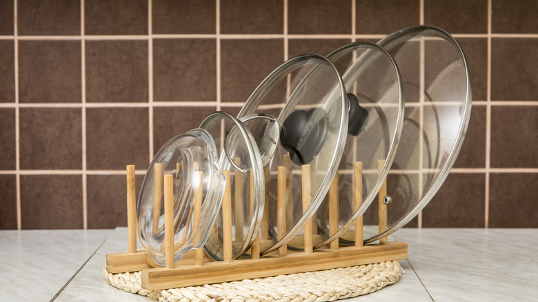 Several pot lids placed on a wooden pot lid holder