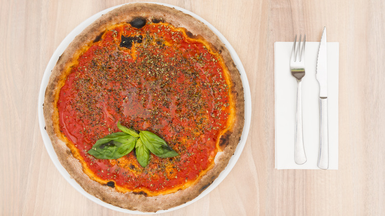 Top view of a a whole pizza marinara pie on table with cutlery