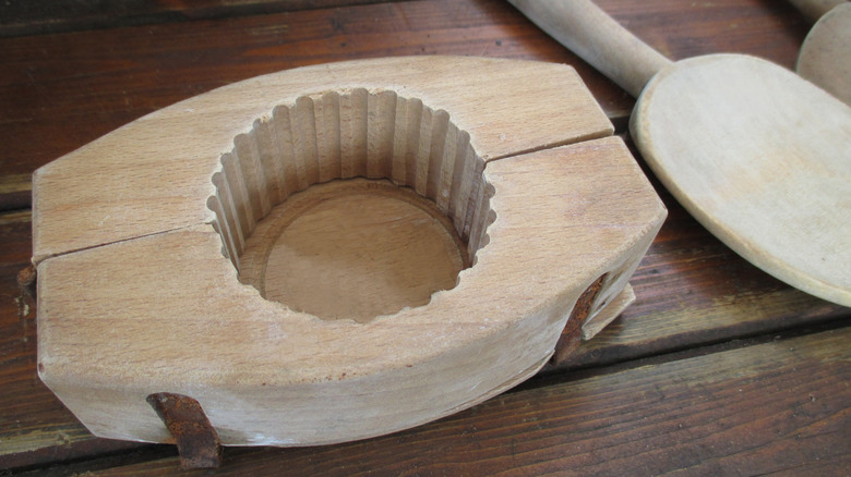 A ridged wooden butter mold on a wood table